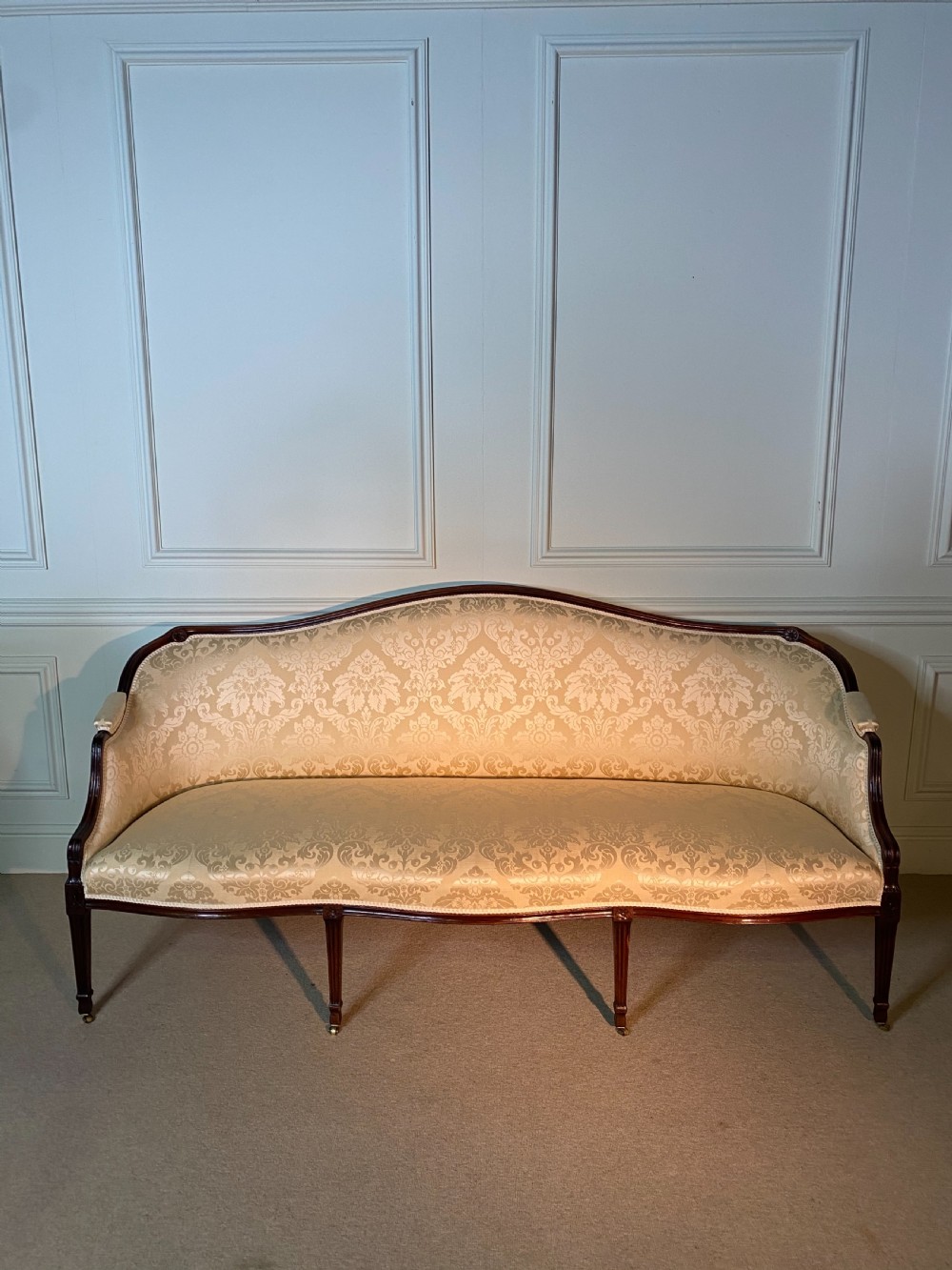 A George III Hepplewhite sofa featuring a serpentine back upholstered in cream damask fabric with dark mahogany reeded legs. View V