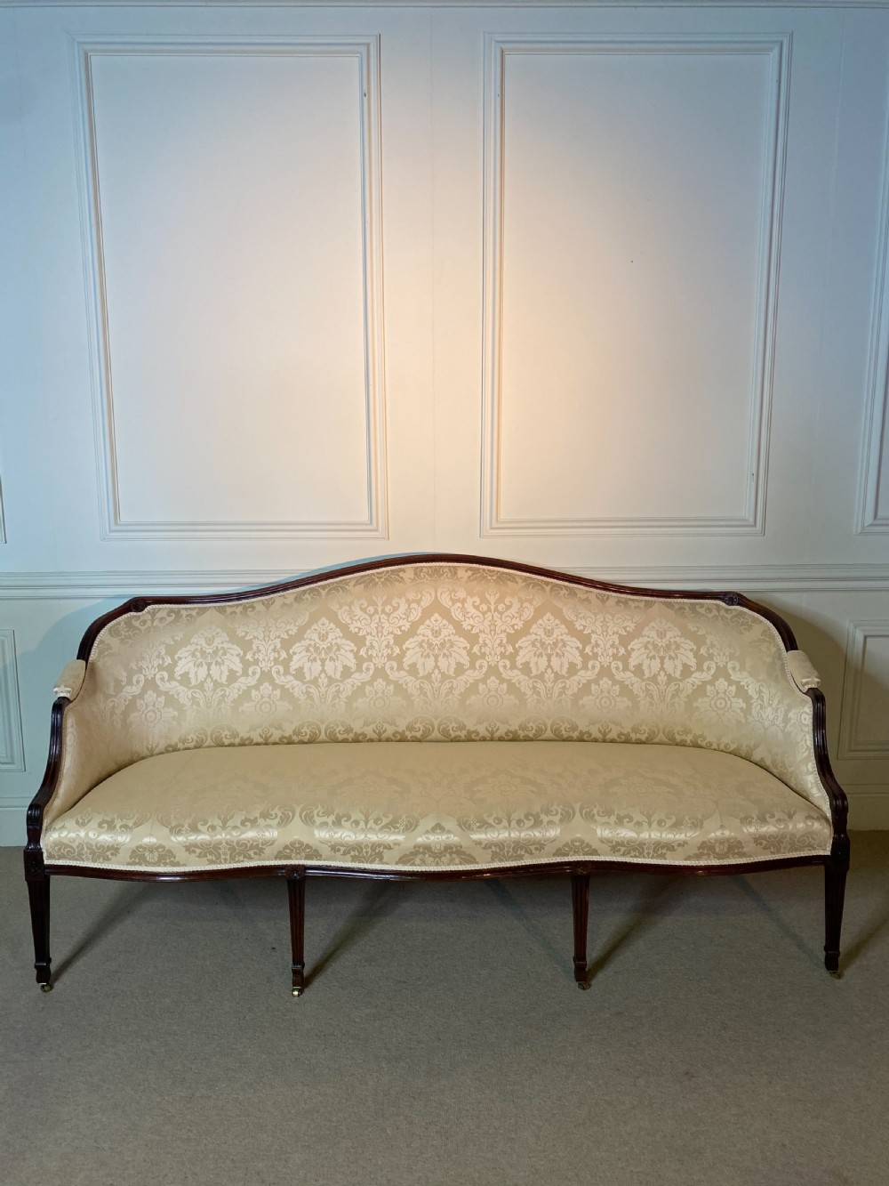 A George III Hepplewhite sofa featuring a serpentine back upholstered in cream damask fabric with dark mahogany reeded legs. View VI