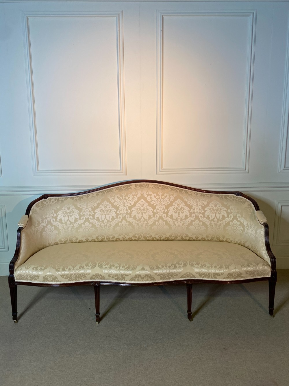 A George III Hepplewhite sofa featuring a serpentine back upholstered in cream damask fabric with dark mahogany reeded legs. View IX