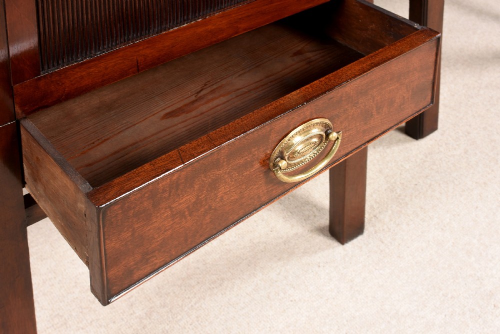 A pair of 18th-century George III mahogany bedside commodes featuring tray tops with handles, tambour shutter doors, and brass drawer handles. View VI