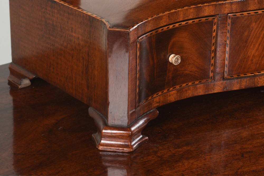 An antique George III mahogany dressing table mirror featuring an oval swing glass on curved supports above a serpentine base with three inlaid drawers. View III