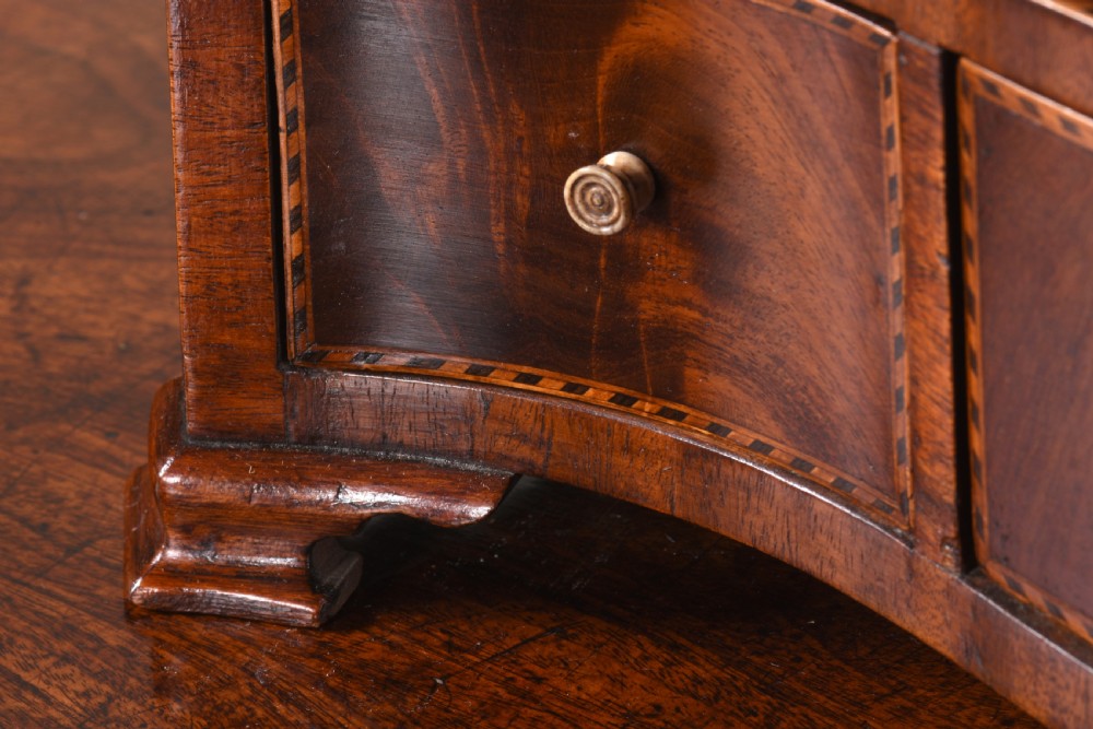 An antique George III mahogany dressing table mirror featuring an oval swing glass on curved supports above a serpentine base with three inlaid drawers. View V