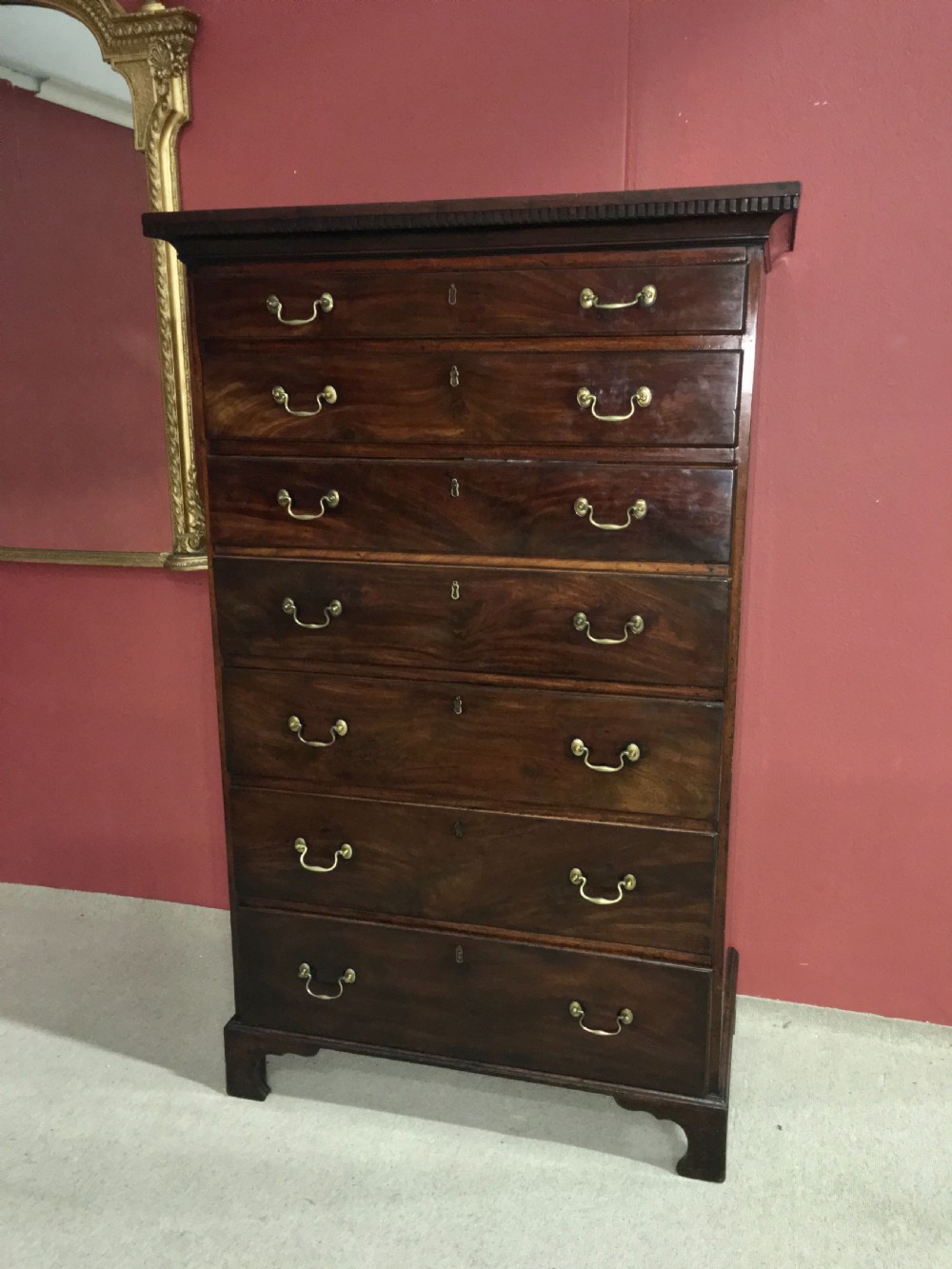 A tall George III mahogany secretaire tallboy featuring seven graduated drawers, brass swan-neck handles, dentil moulding, and bracket feet. View III