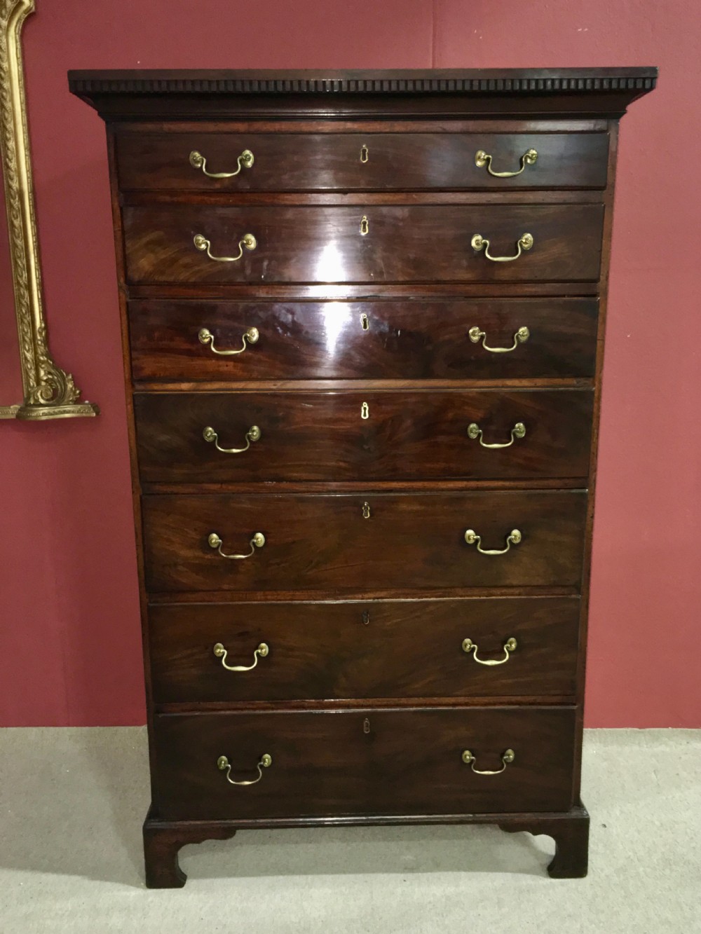 A tall George III mahogany secretaire tallboy featuring seven graduated drawers, brass swan-neck handles, dentil moulding, and bracket feet. View V