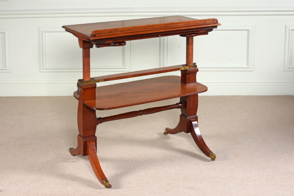 A George III mahogany architects table featuring an adjustable height mechanism, tilting top slope with book ledge, lower tier shelf, and splayed legs on brass castors.