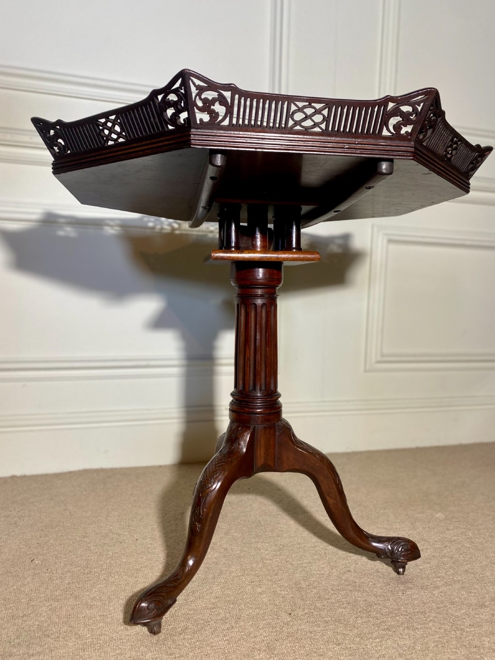 An 18th-century mahogany octagonal tripod table featuring a pierced fretwork gallery, fluted central column, and carved cabriole legs. View XVI