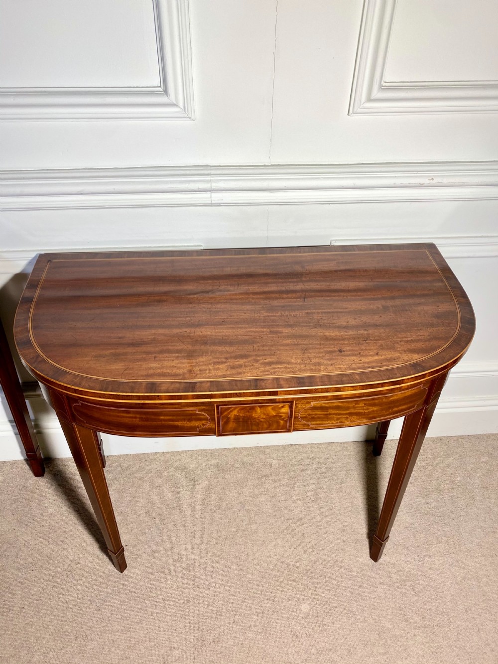A pair of 18th-century George III mahogany demilune card tables with satinwood crossbanding, boxwood stringing, and square tapered legs. View V