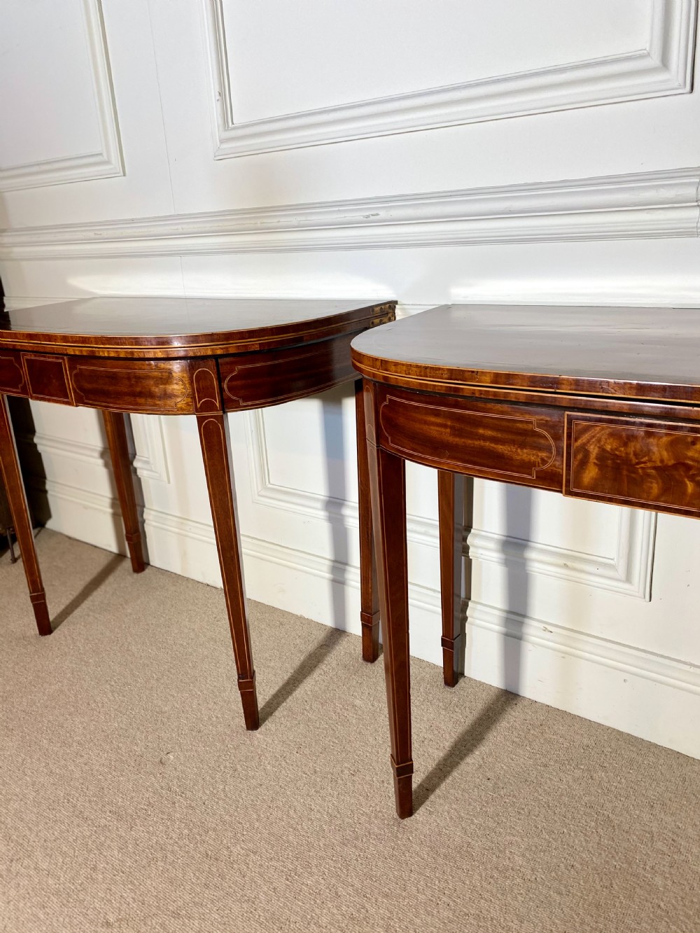 A pair of 18th-century George III mahogany demilune card tables with satinwood crossbanding, boxwood stringing, and square tapered legs. View X