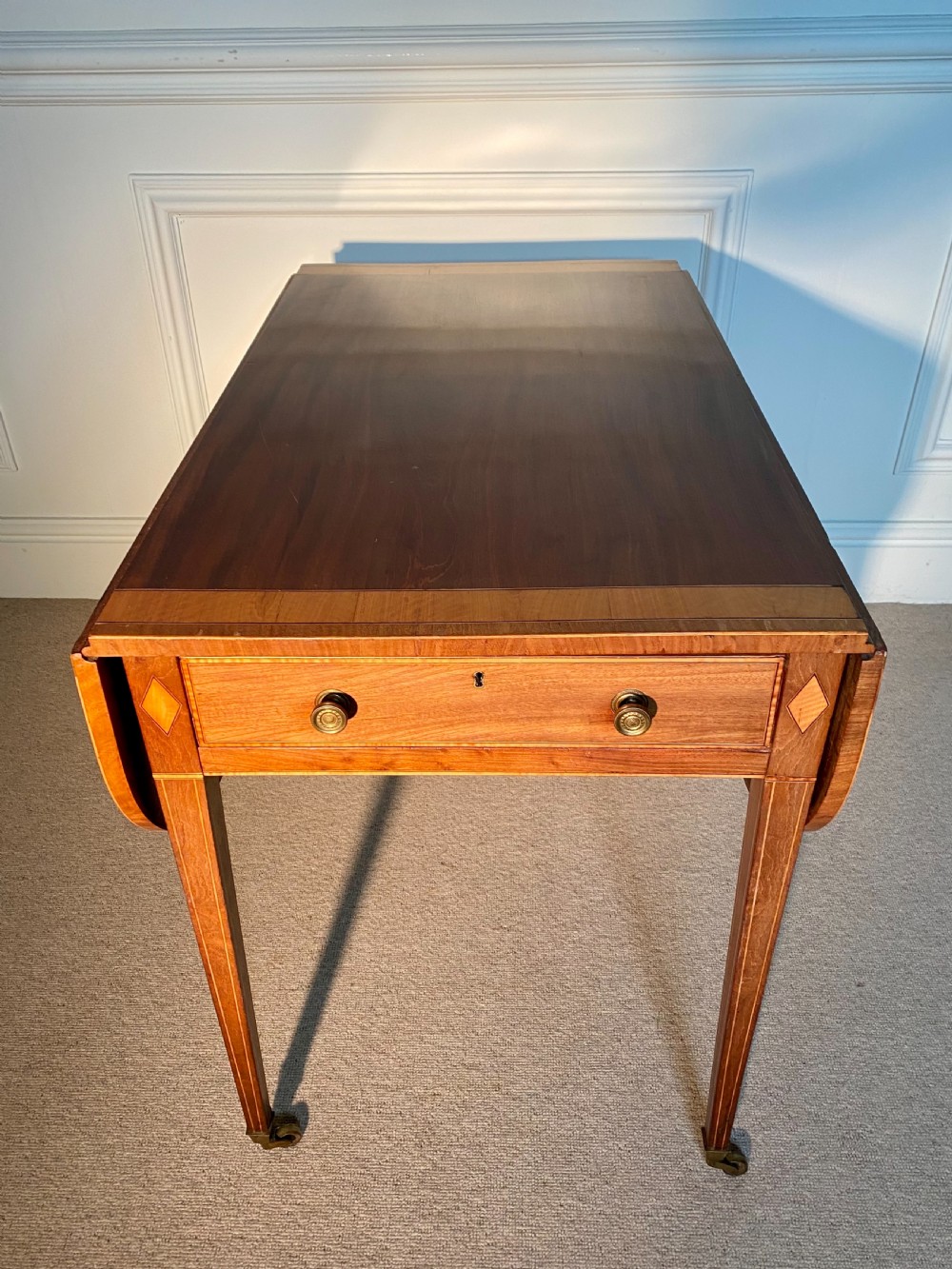 An 18th-century Sheraton mahogany Pembroke table featuring drop leaves, stringing inlay, a single drawer with brass knobs, and square tapered legs on brass castors. View III