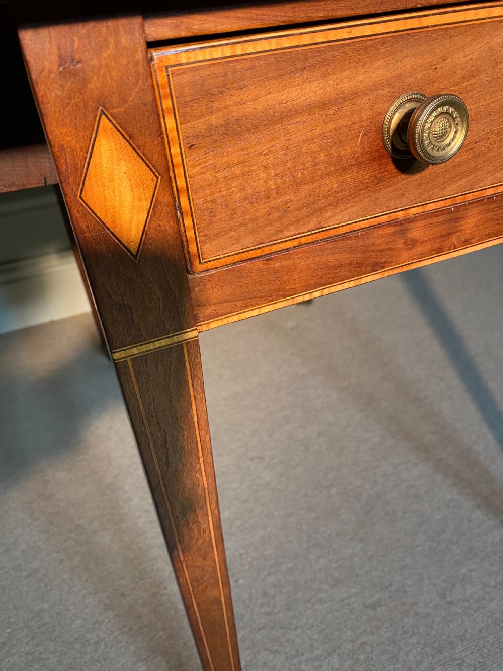An 18th-century Sheraton mahogany Pembroke table featuring drop leaves, stringing inlay, a single drawer with brass knobs, and square tapered legs on brass castors. View IX