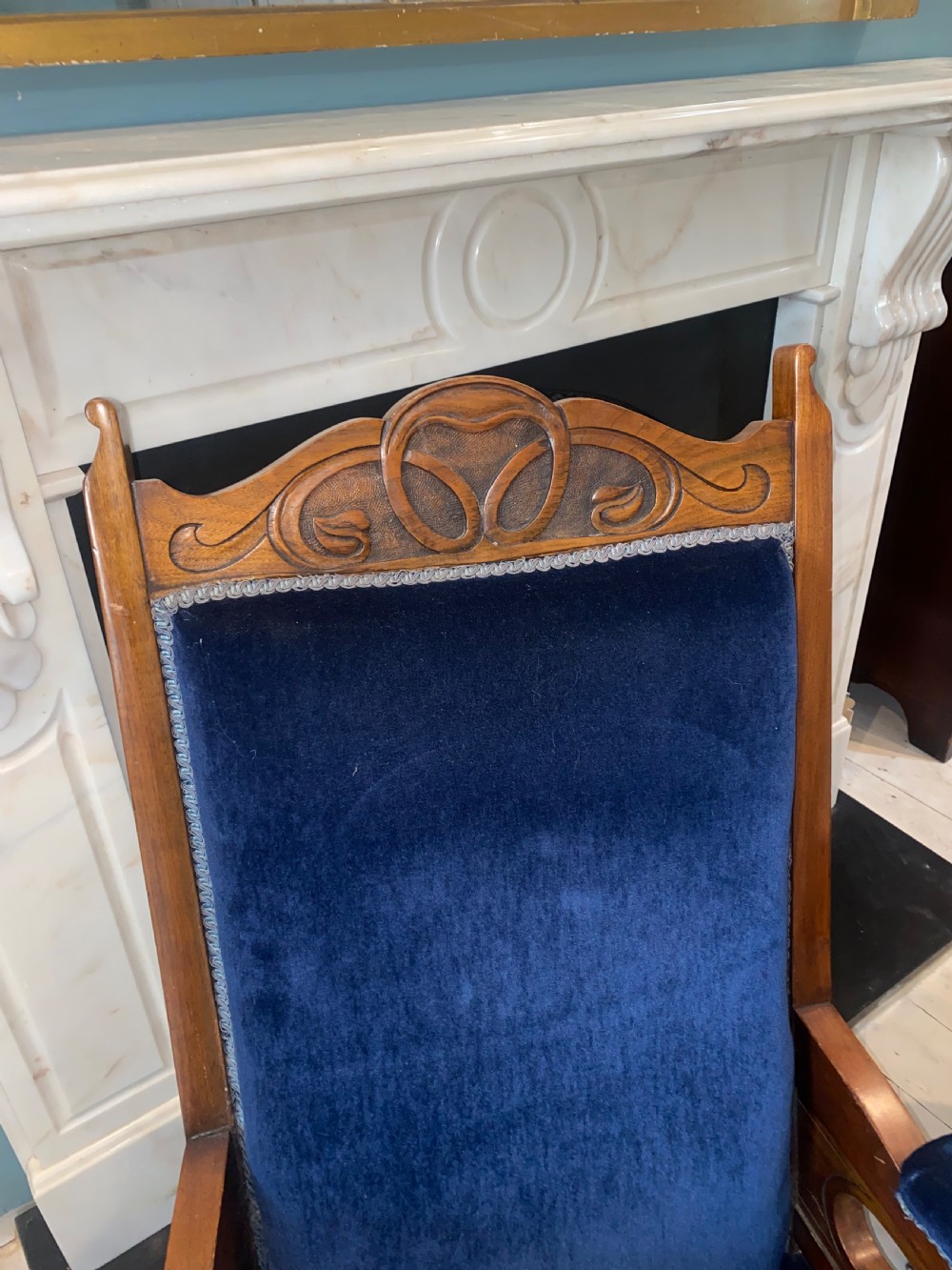 A pair of 19th-century walnut armchairs featuring carved crest rails, padded armrests, brass castors, and deep navy blue velvet upholstery. View VI