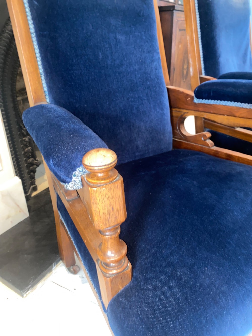 A pair of 19th-century walnut armchairs featuring carved crest rails, padded armrests, brass castors, and deep navy blue velvet upholstery. View VII