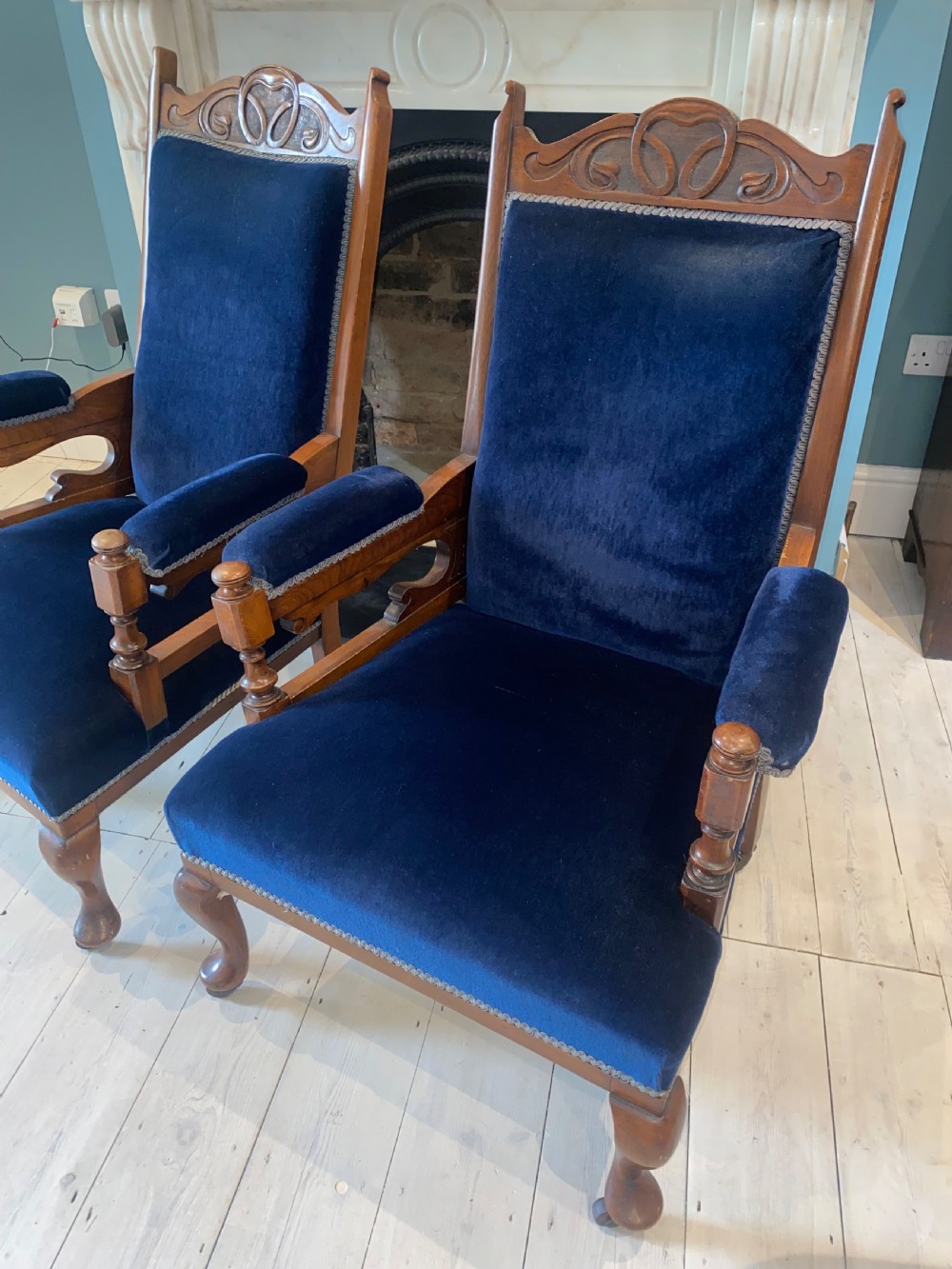 A pair of 19th-century walnut armchairs featuring carved crest rails, padded armrests, brass castors, and deep navy blue velvet upholstery. View VIII