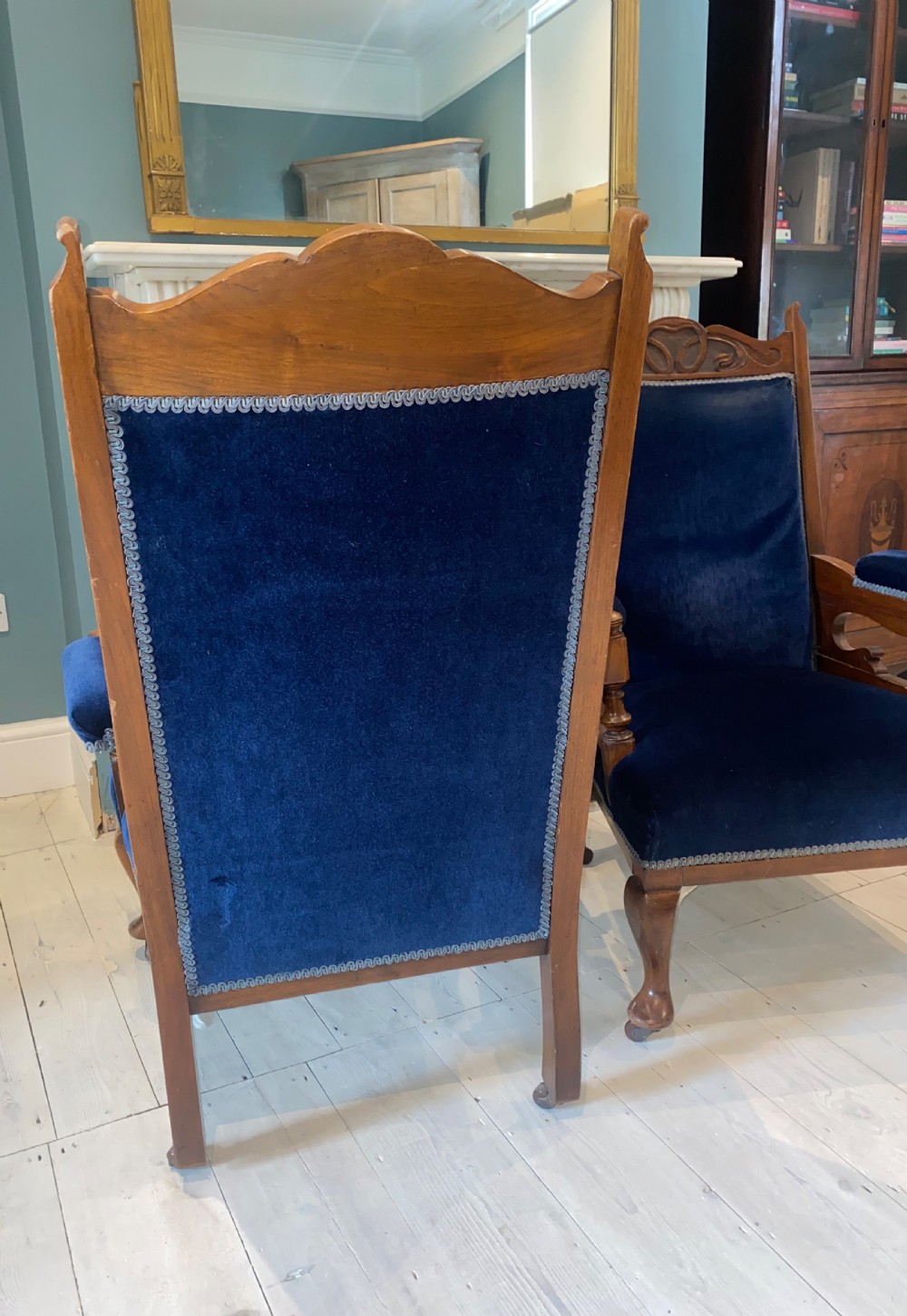 A pair of 19th-century walnut armchairs featuring carved crest rails, padded armrests, brass castors, and deep navy blue velvet upholstery. View IX