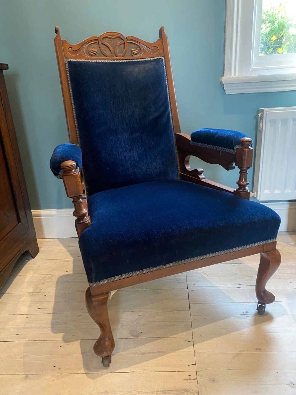 A pair of 19th-century walnut armchairs featuring carved crest rails, padded armrests, brass castors, and deep navy blue velvet upholstery. View XI