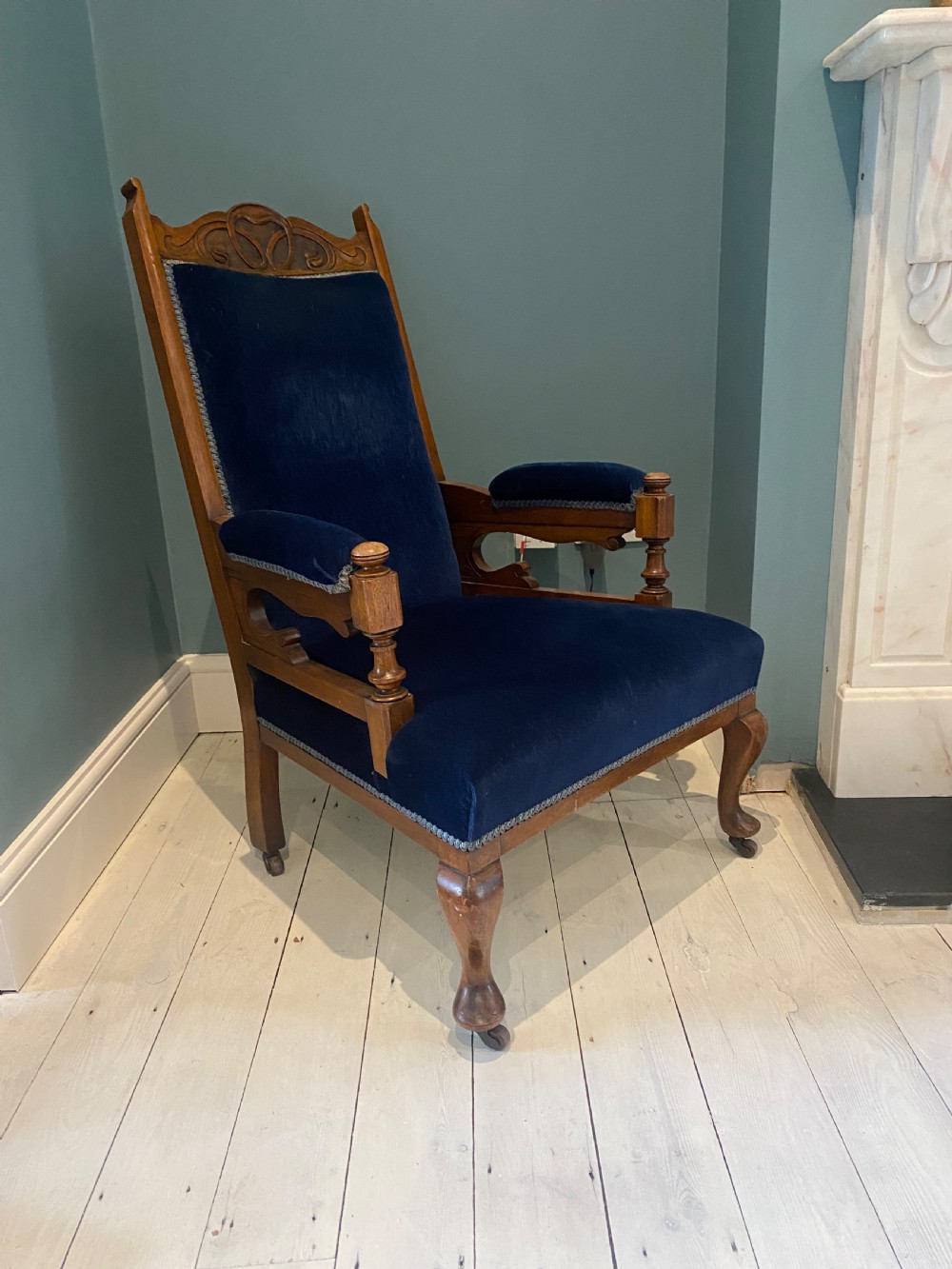 A pair of 19th-century walnut armchairs featuring carved crest rails, padded armrests, brass castors, and deep navy blue velvet upholstery. View XIII