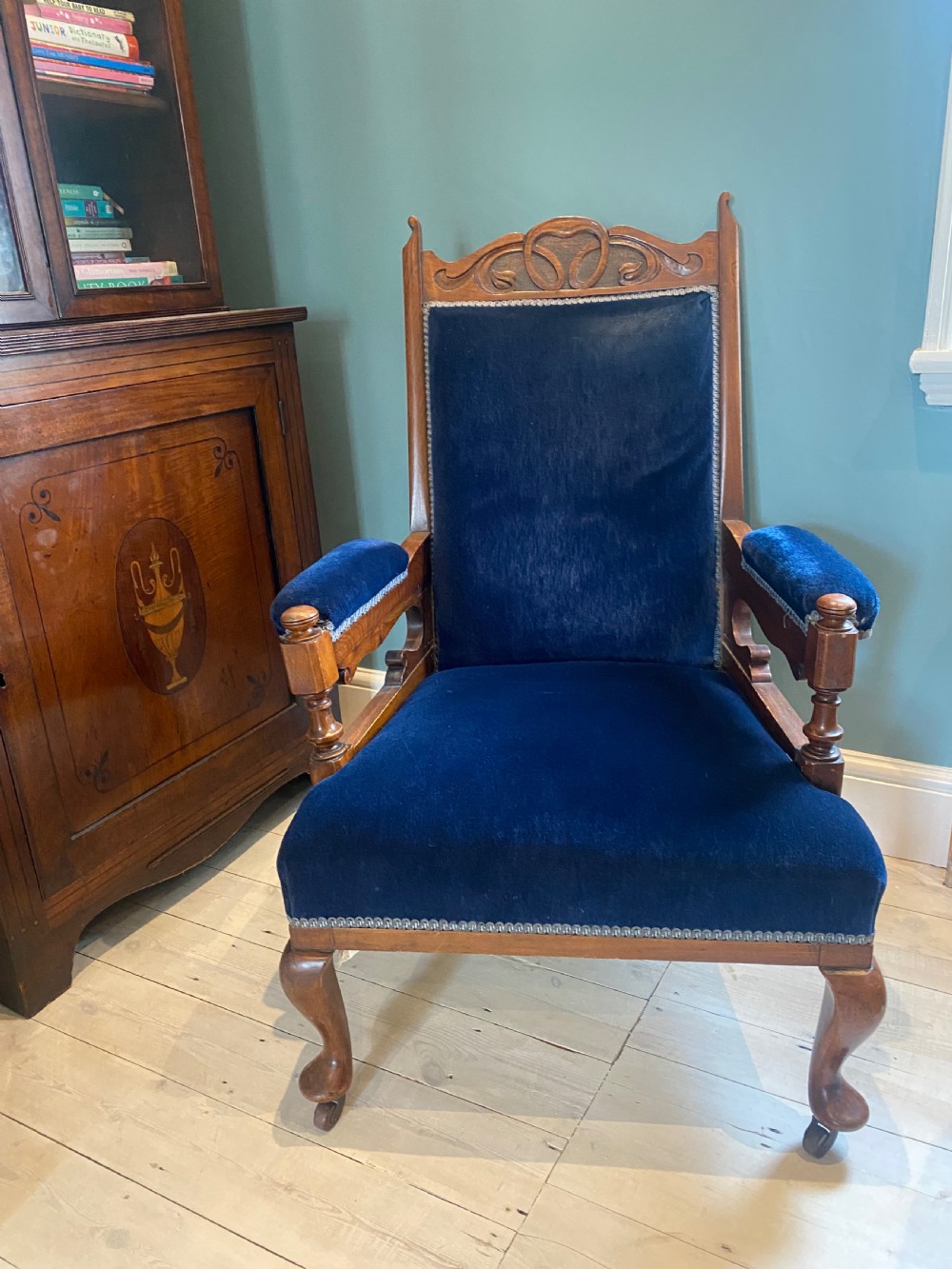 A pair of 19th-century walnut armchairs featuring carved crest rails, padded armrests, brass castors, and deep navy blue velvet upholstery. View XVI