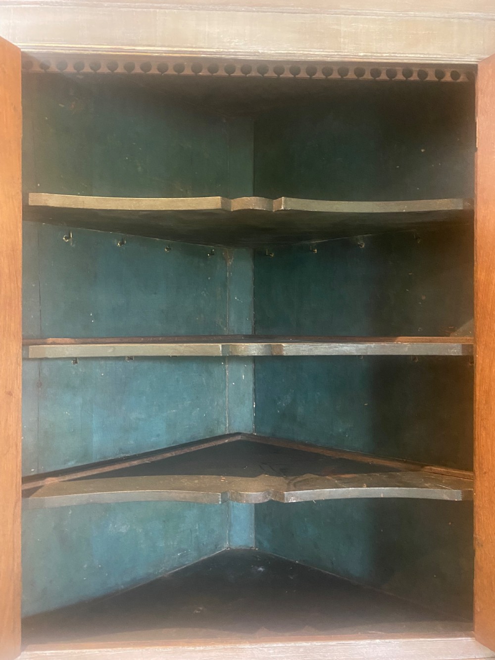An 18th-century two-tier limed oak corner cupboard featuring raised panel doors, a moulded cornice, and a plinth base. View VIII