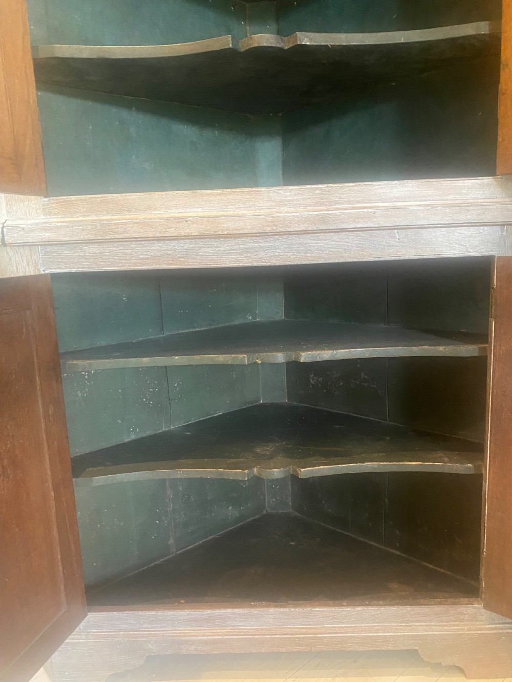 An 18th-century two-tier limed oak corner cupboard featuring raised panel doors, a moulded cornice, and a plinth base. View IX