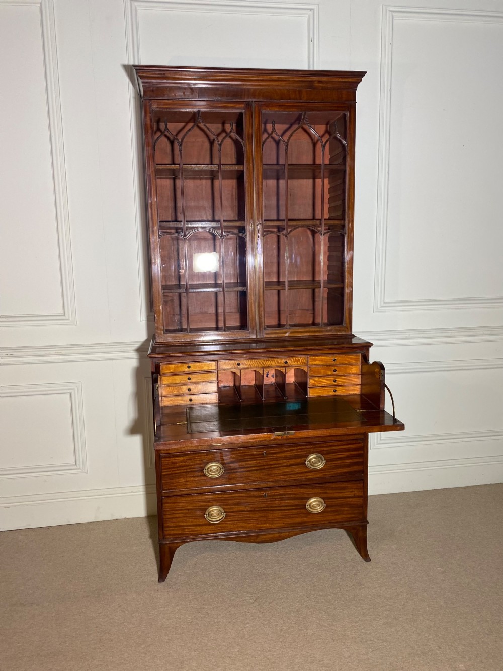 An 18th-century George III mahogany secretaire bookcase featuring an upper double-door glazed cabinet with arched astragal glazing, an open drop-front writing drawer with internal pigeonholes, and lower drawers with brass oval handles. View V