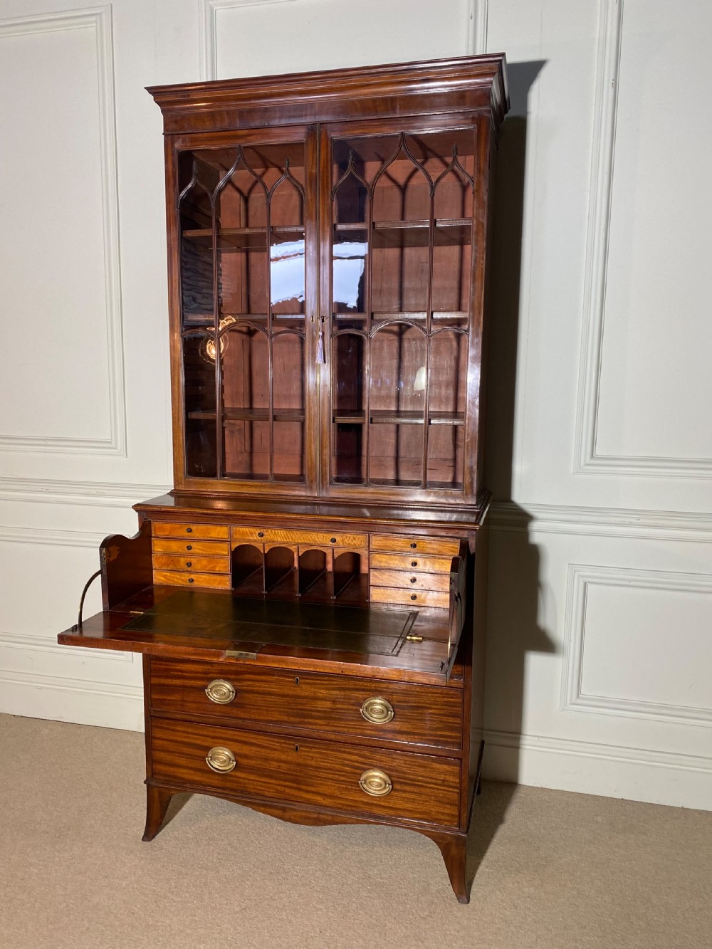 An 18th-century George III mahogany secretaire bookcase featuring an upper double-door glazed cabinet with arched astragal glazing, an open drop-front writing drawer with internal pigeonholes, and lower drawers with brass oval handles. View IX
