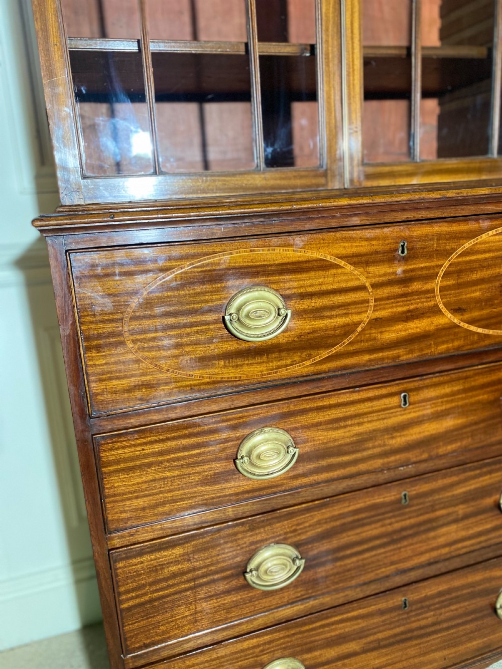 An 18th-century George III mahogany secretaire bookcase featuring an upper double-door glazed cabinet with arched astragal glazing, an open drop-front writing drawer with internal pigeonholes, and lower drawers with brass oval handles. View X
