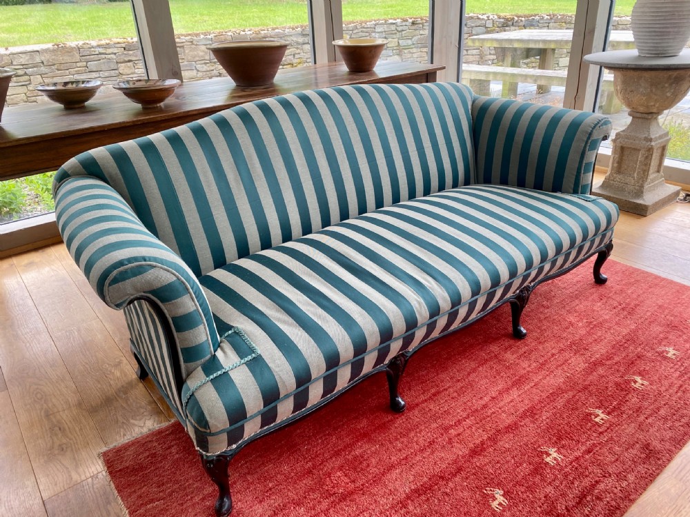 A 19th-century scroll arm sofa upholstered in green and beige striped fabric with dark carved cabriole legs.