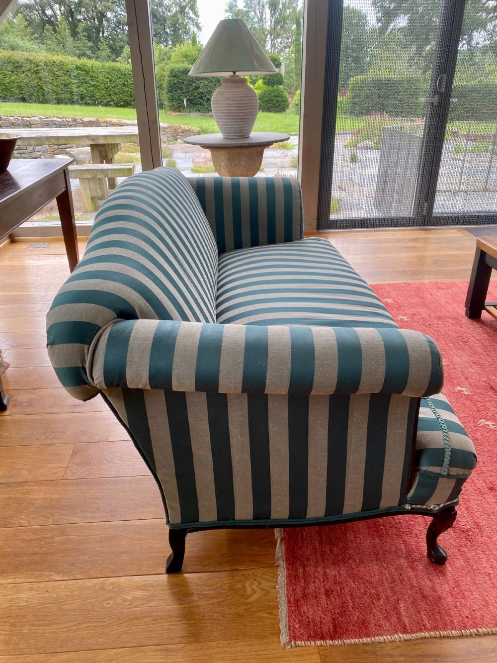 A 19th-century scroll arm sofa upholstered in green and beige striped fabric with dark carved cabriole legs. View III