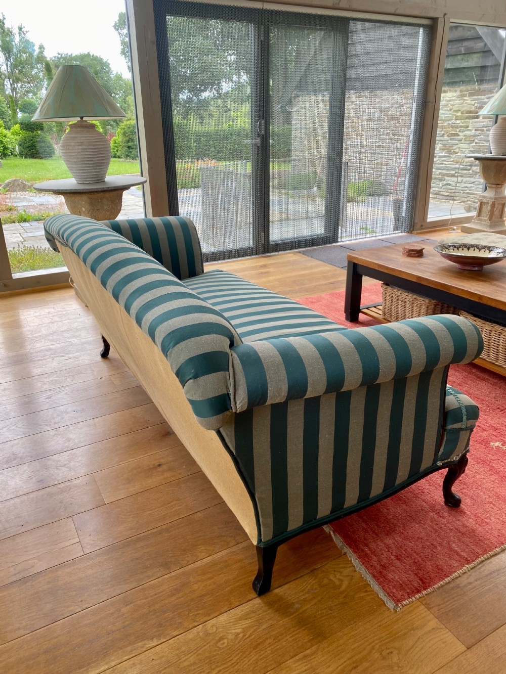 A 19th-century scroll arm sofa upholstered in green and beige striped fabric with dark carved cabriole legs. View V