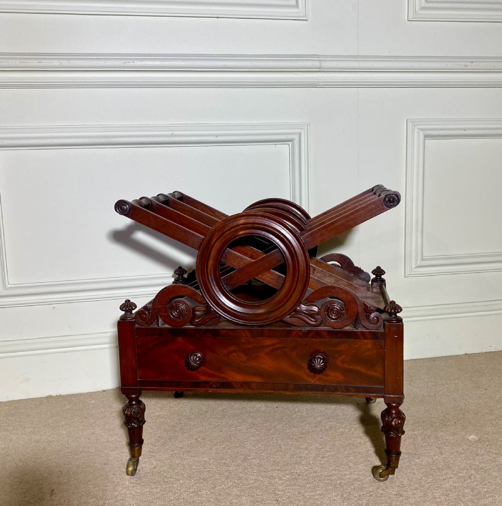 A Regency mahogany music canterbury featuring circular divided compartments, carved rosettes, a lower drawer with turned knobs, and carved legs on brass castors. View II