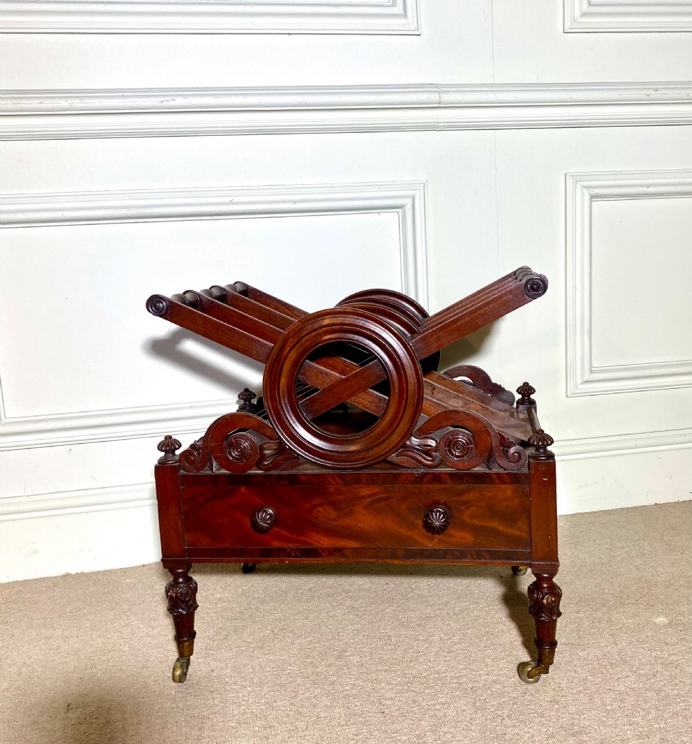 A Regency mahogany music canterbury featuring circular divided compartments, carved rosettes, a lower drawer with turned knobs, and carved legs on brass castors. View III