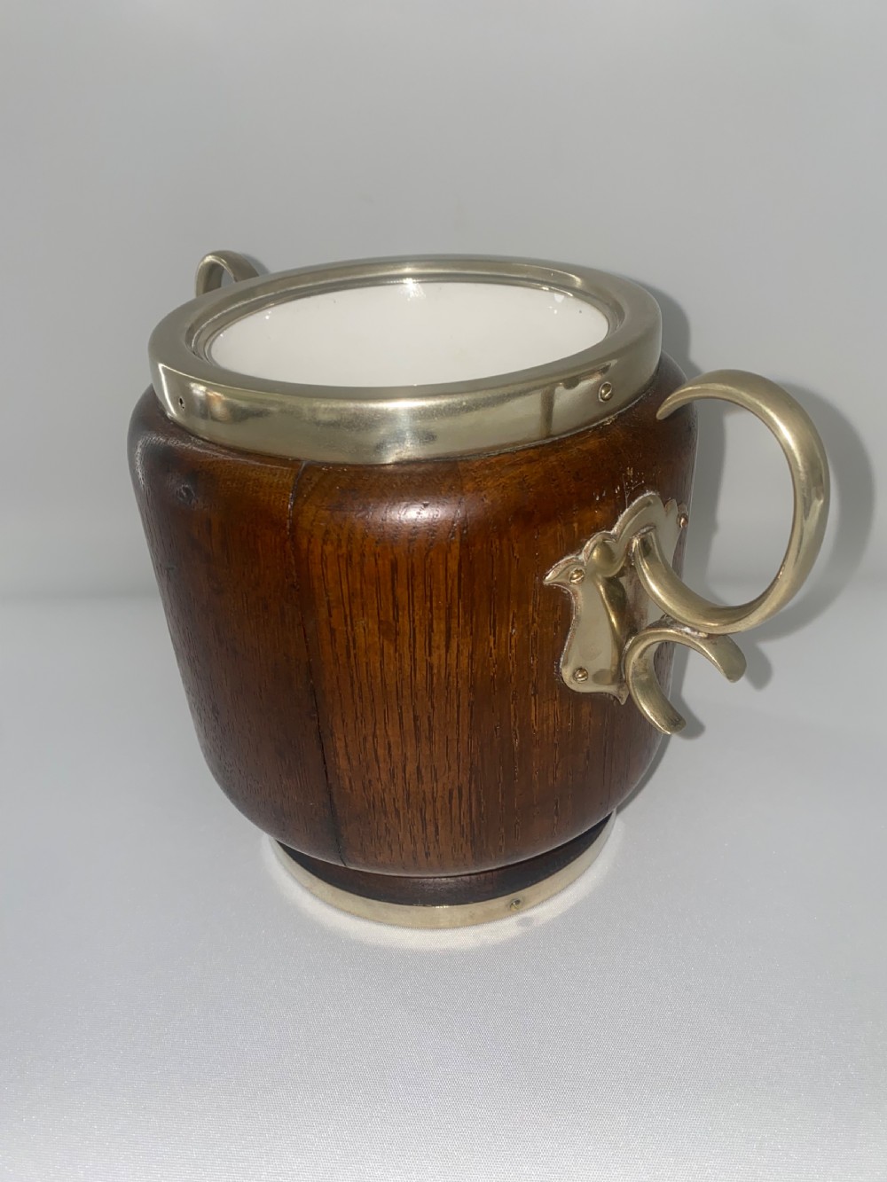A turned oak ice bucket featuring silver-plated scroll handles, a shield-shaped front cartouche, and a domed metal lid with a finial. View V