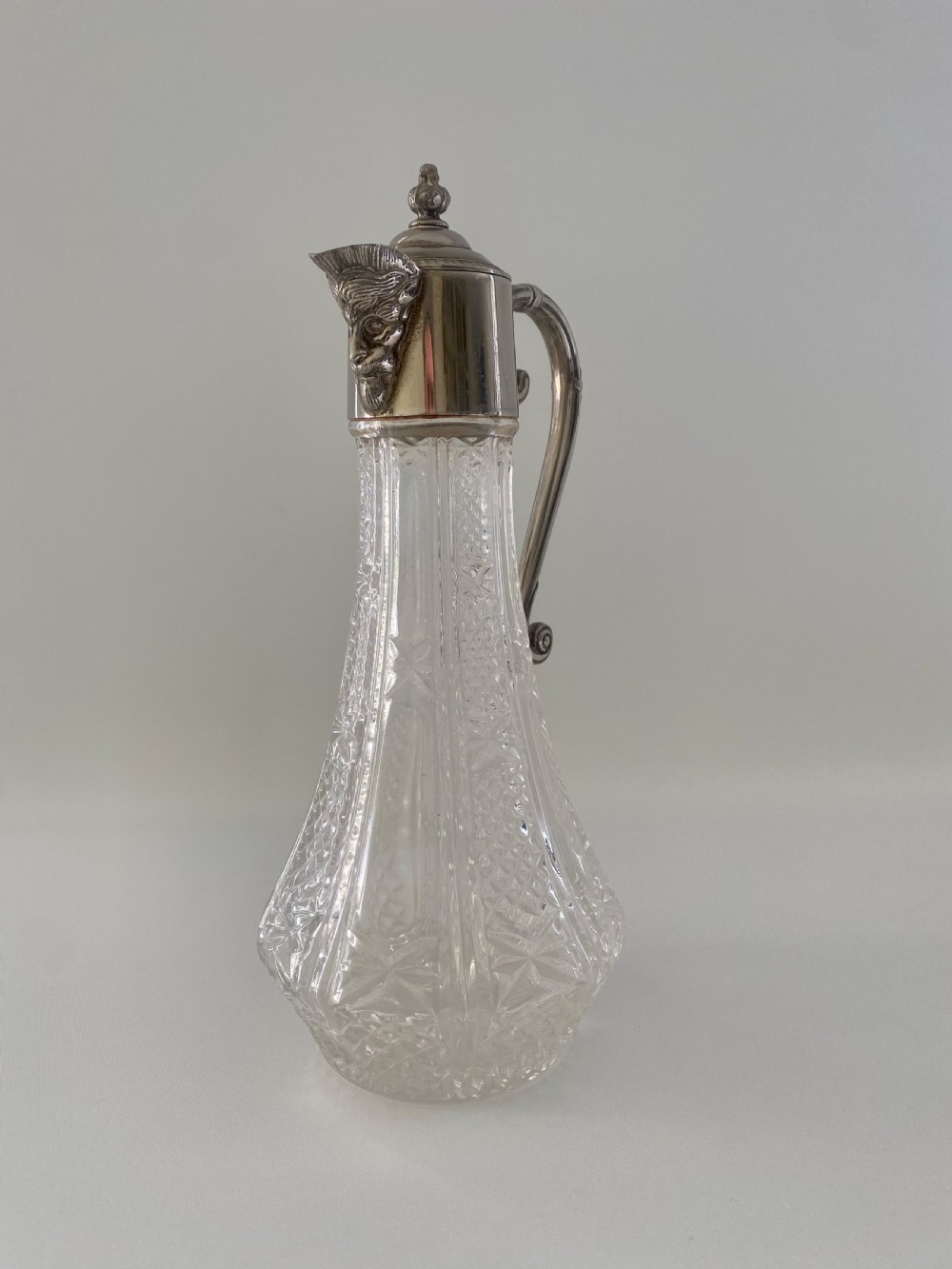 A cut crystal claret jug featuring a silver-plated collar, a mascaron face spout, and an ornate scroll handle. View II