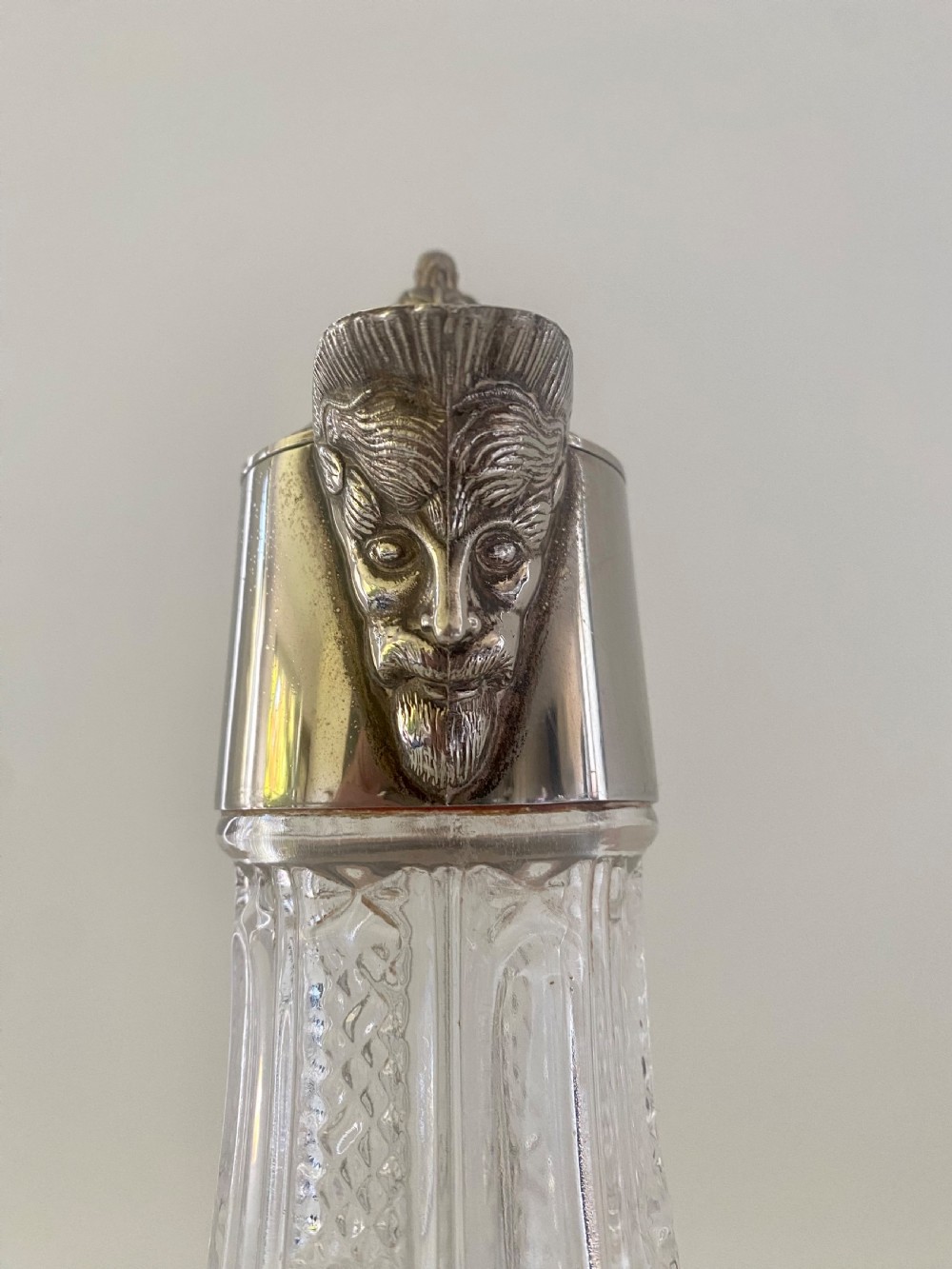 A cut crystal claret jug featuring a silver-plated collar, a mascaron face spout, and an ornate scroll handle. View VII