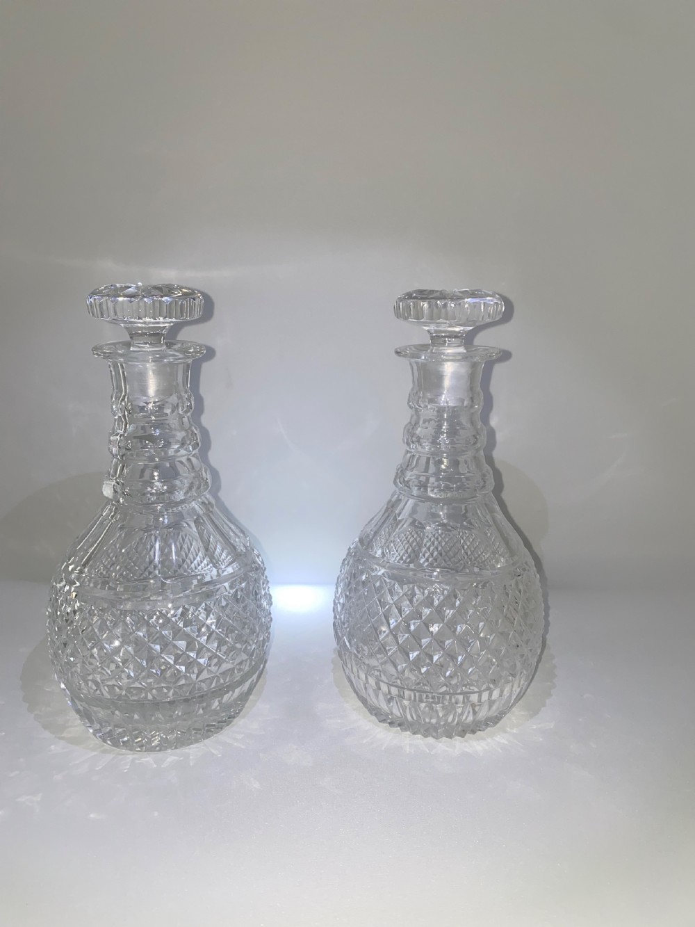A pair of clear cut crystal glass decanters featuring diamond-cut lower bodies, ringed necks, and disc-shaped glass stoppers. View II