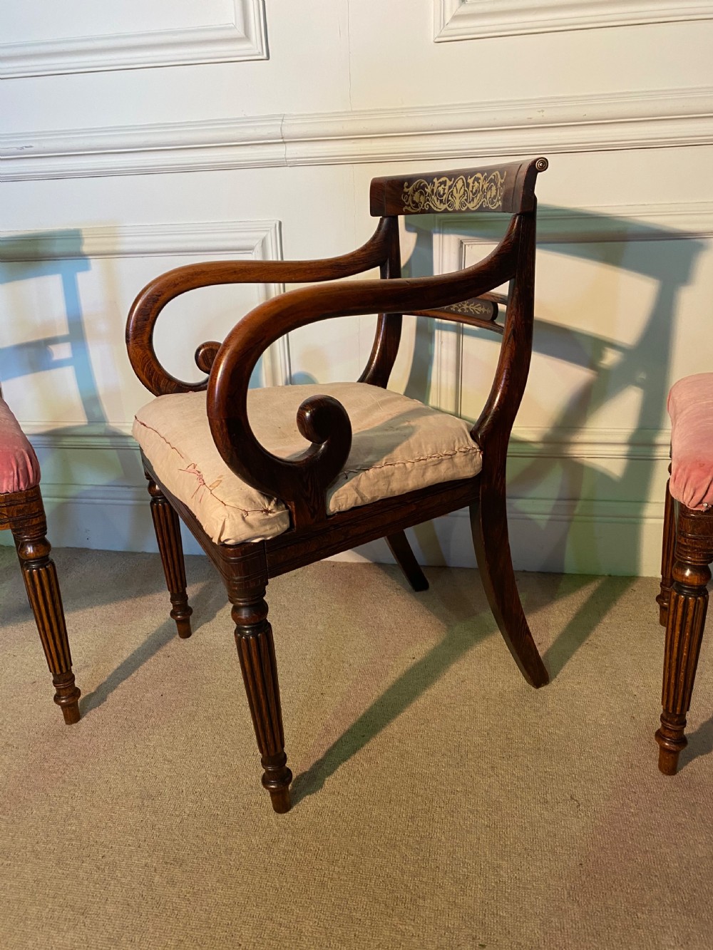 A set of Regency wooden dining chairs featuring brass inlay on the top rails, turned fluted legs, and upholstered drop-in seats. View V
