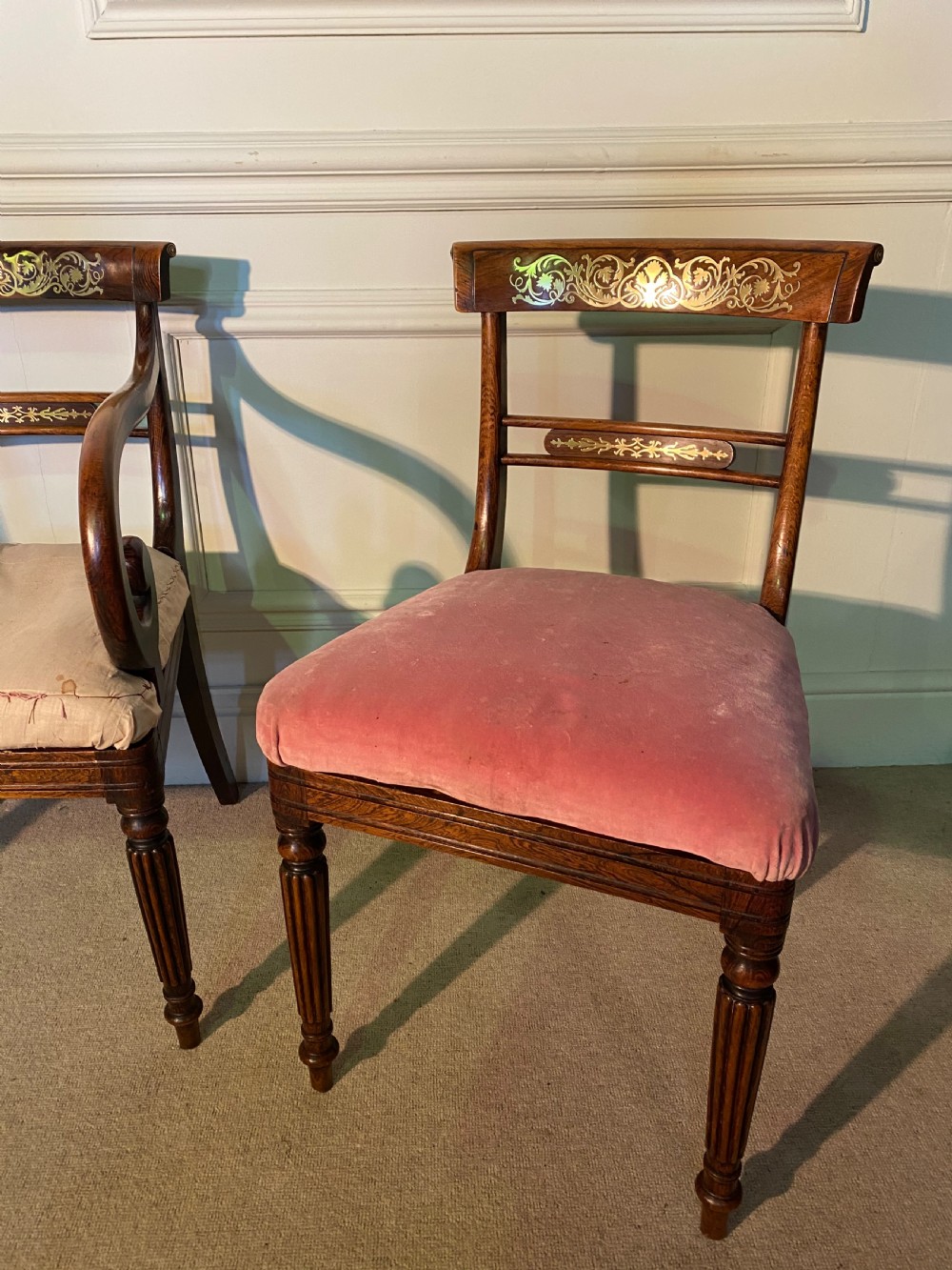 A set of Regency wooden dining chairs featuring brass inlay on the top rails, turned fluted legs, and upholstered drop-in seats. View VI