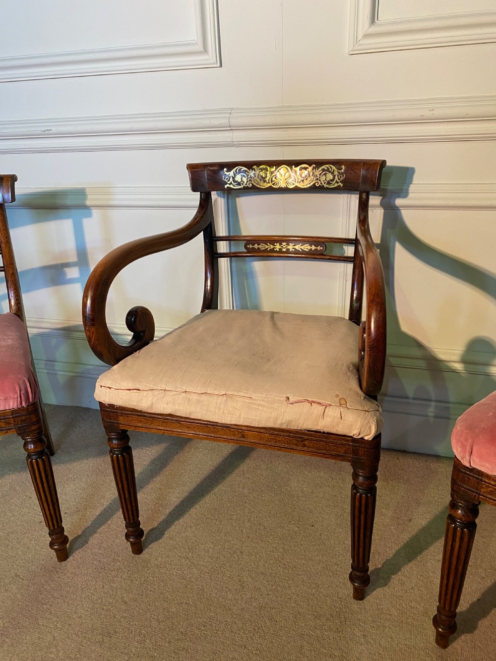A set of Regency wooden dining chairs featuring brass inlay on the top rails, turned fluted legs, and upholstered drop-in seats. View VII