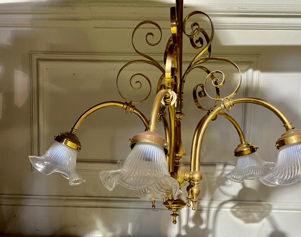 An Art Deco five-arm brass chandelier featuring scrolled upper accents and downward-facing ribbed frosted glass shades. View III