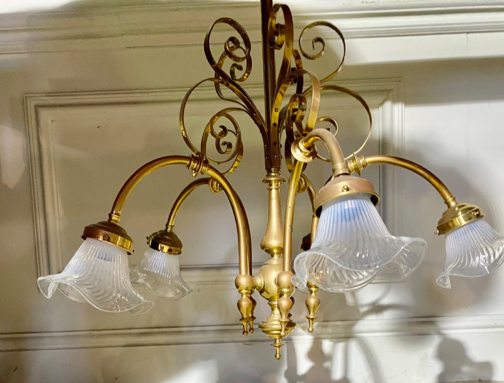 An Art Deco five-arm brass chandelier featuring scrolled upper accents and downward-facing ribbed frosted glass shades. View IV