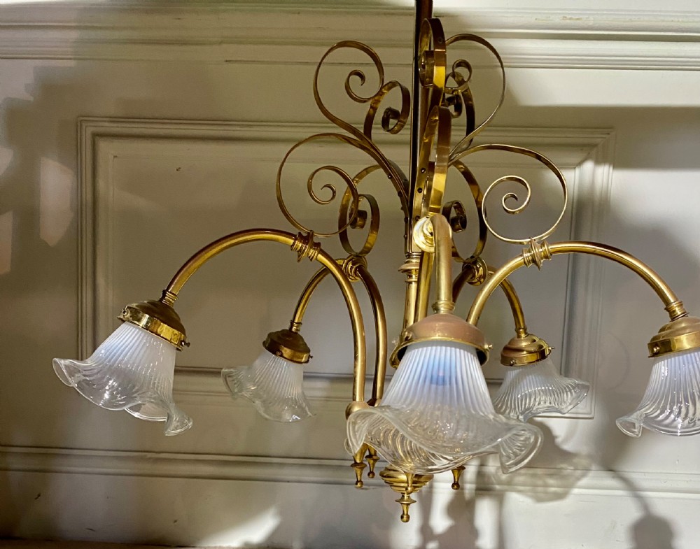 An Art Deco five-arm brass chandelier featuring scrolled upper accents and downward-facing ribbed frosted glass shades. View V