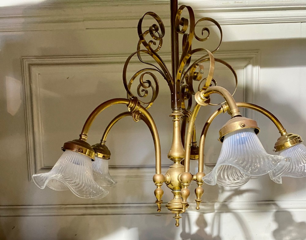 An Art Deco five-arm brass chandelier featuring scrolled upper accents and downward-facing ribbed frosted glass shades. View VI
