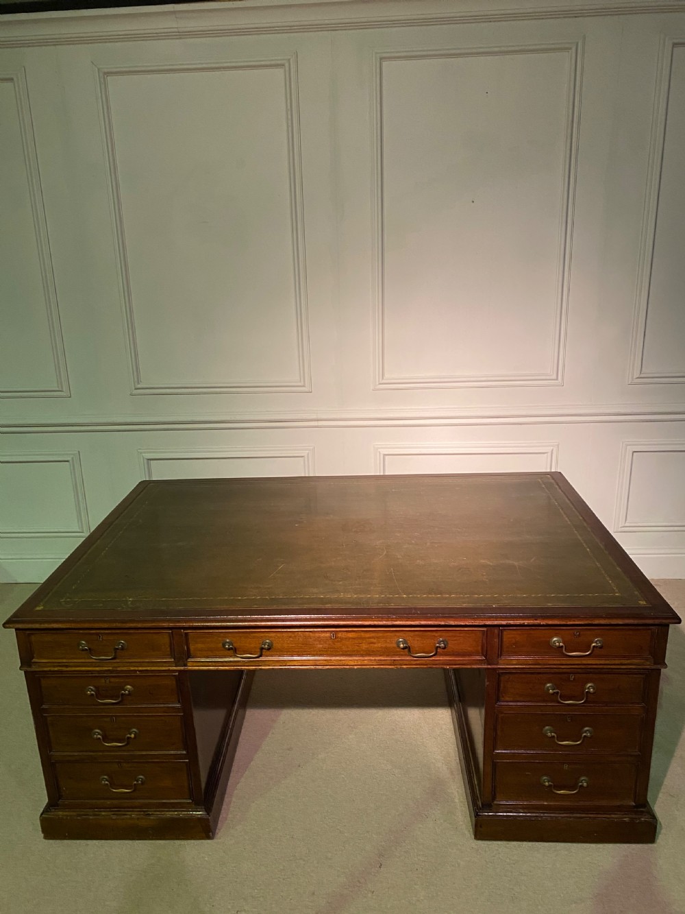 A nineteenth-century mahogany partners desk featuring a green leather inset writing surface, twin drawer pedestals, and brass drop handles. View V