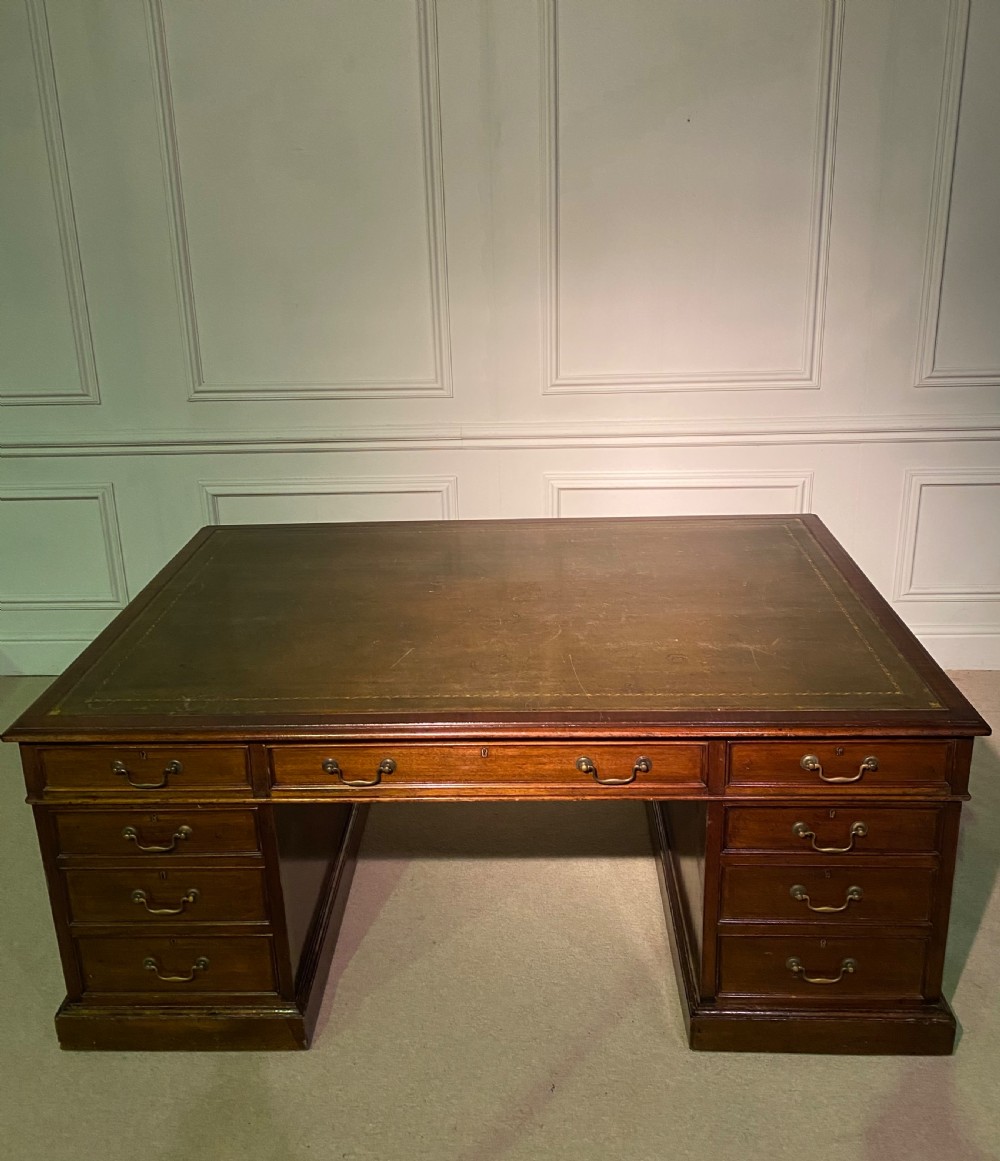 A nineteenth-century mahogany partners desk featuring a green leather inset writing surface, twin drawer pedestals, and brass drop handles. View VI