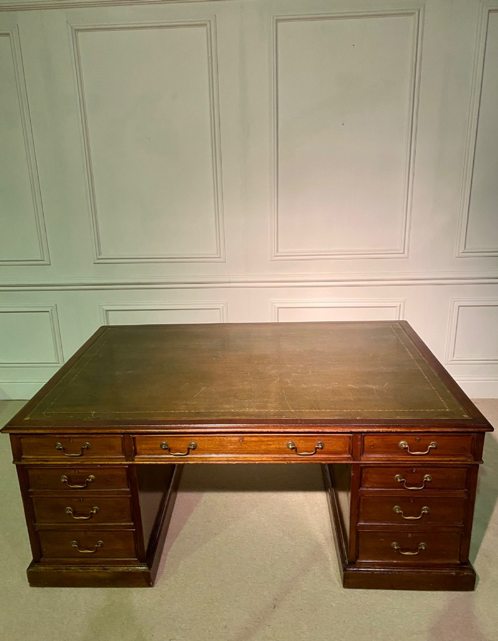 A nineteenth-century mahogany partners desk featuring a green leather inset writing surface, twin drawer pedestals, and brass drop handles. View VII