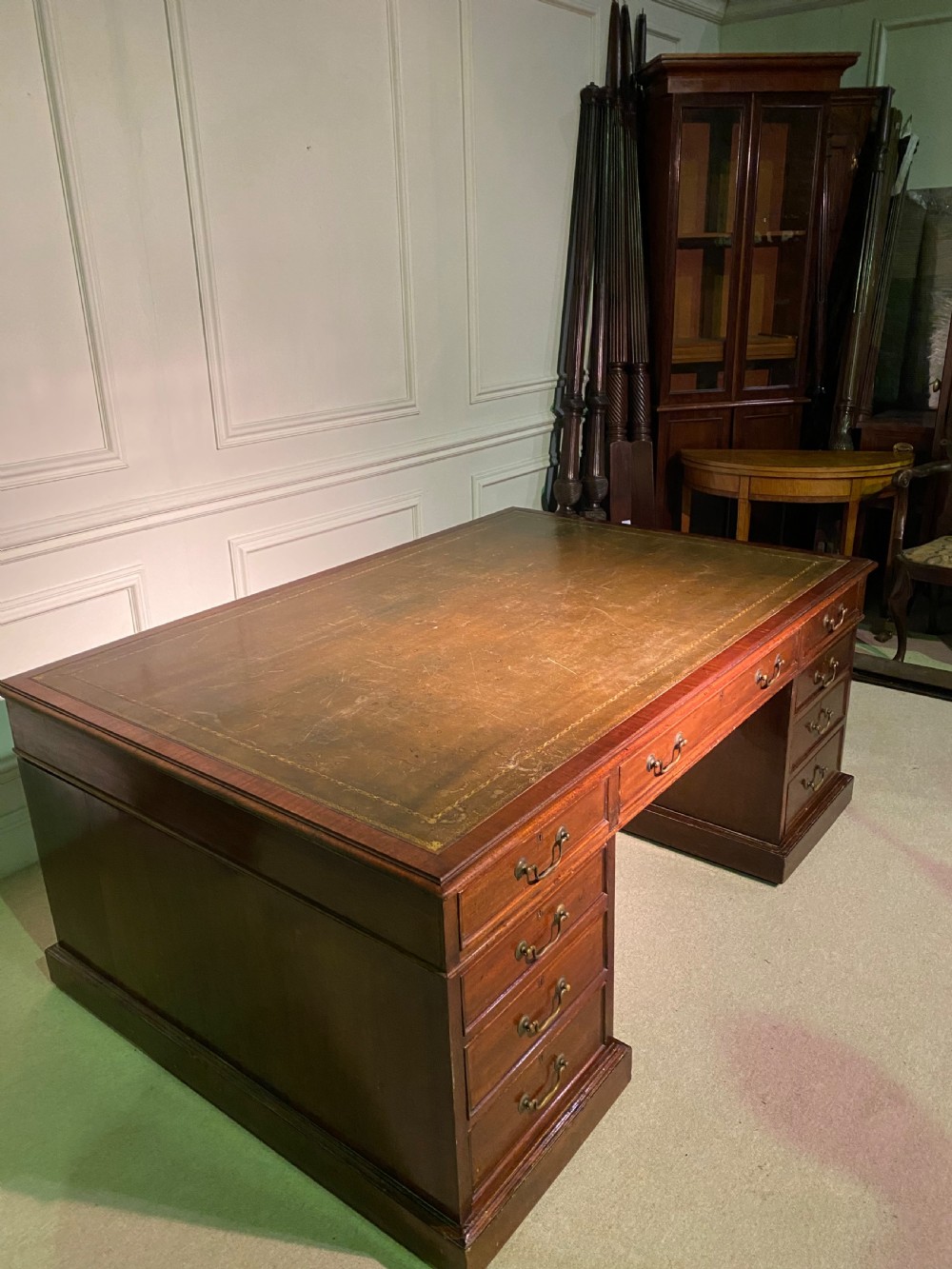 A nineteenth-century mahogany partners desk featuring a green leather inset writing surface, twin drawer pedestals, and brass drop handles. View IX