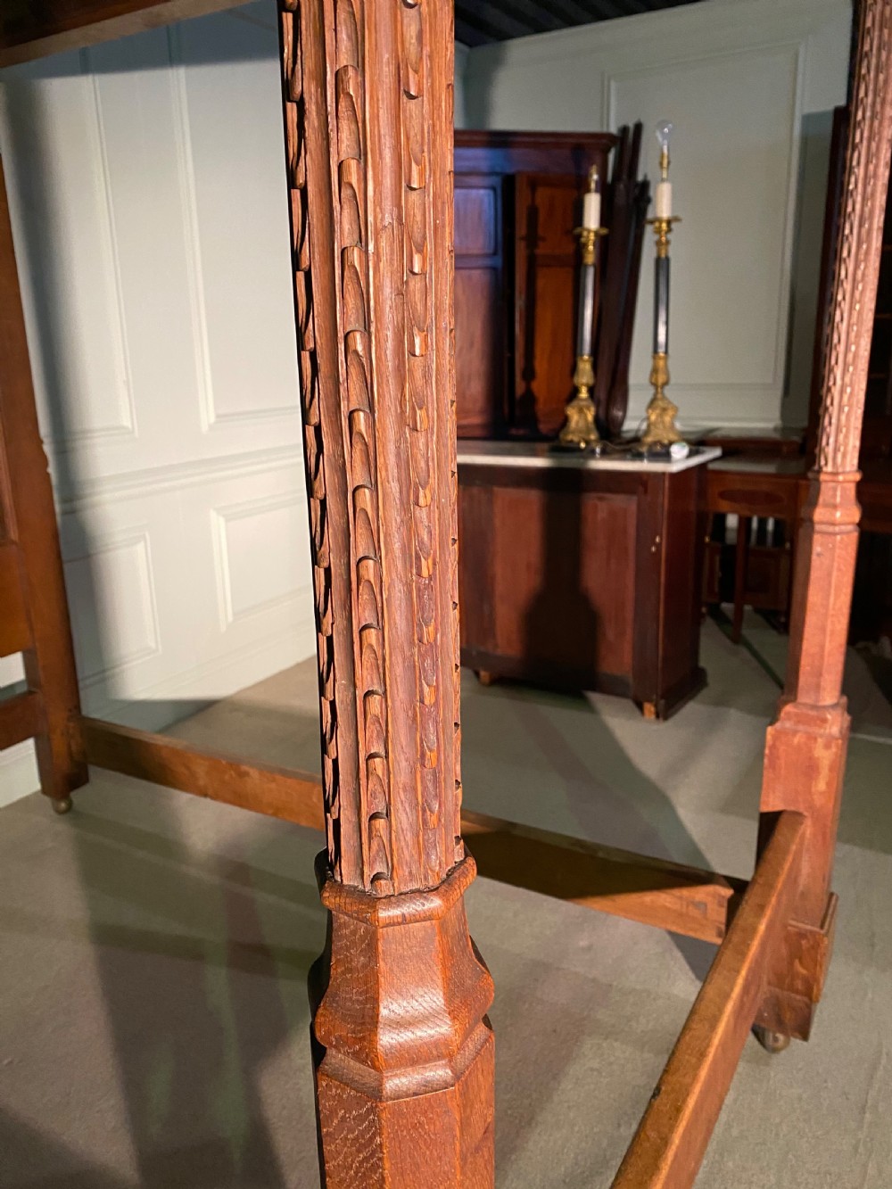 An Arts and Crafts oak four poster bed frame featuring carved upright posts and a decorative upper frieze canopy structure. View VII