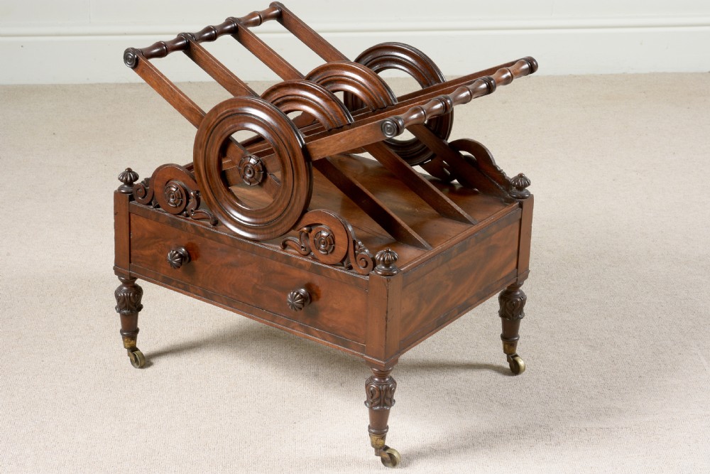 A Regency mahogany music canterbury featuring circular divided compartments, carved rosettes, a lower drawer with turned knobs, and carved legs on brass castors.