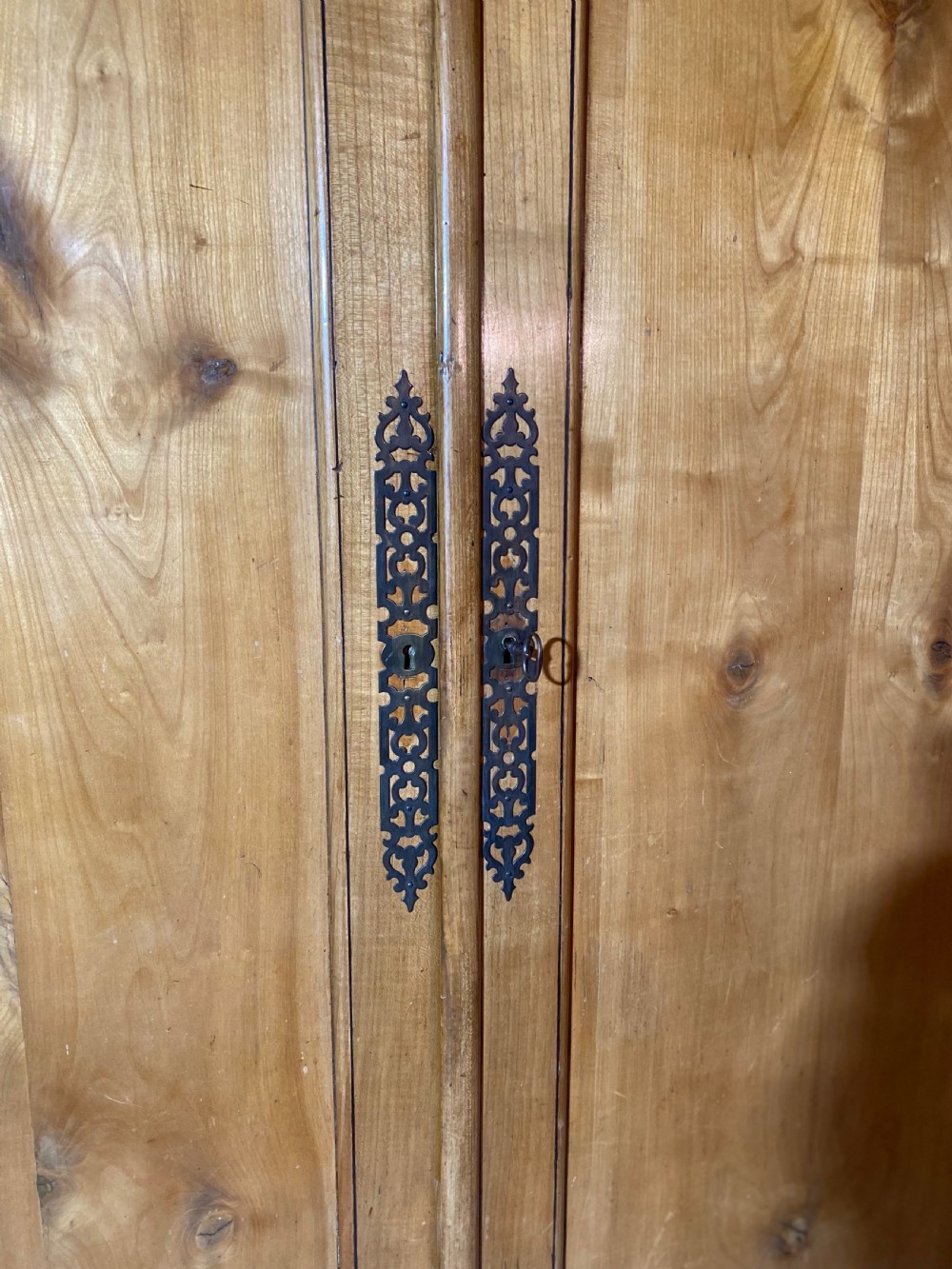 A tall 19th-century cherry wood armoire featuring double panelled doors, decorative iron keyplates, and a projecting upper cornice. View IX