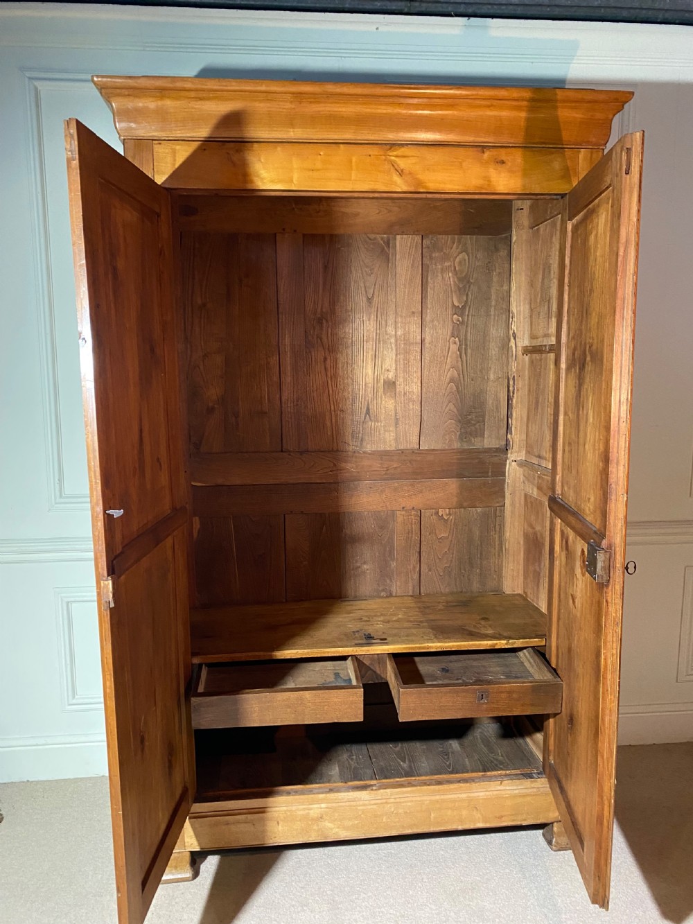 A tall 19th-century cherry wood armoire featuring double panelled doors, decorative iron keyplates, and a projecting upper cornice. View XIII
